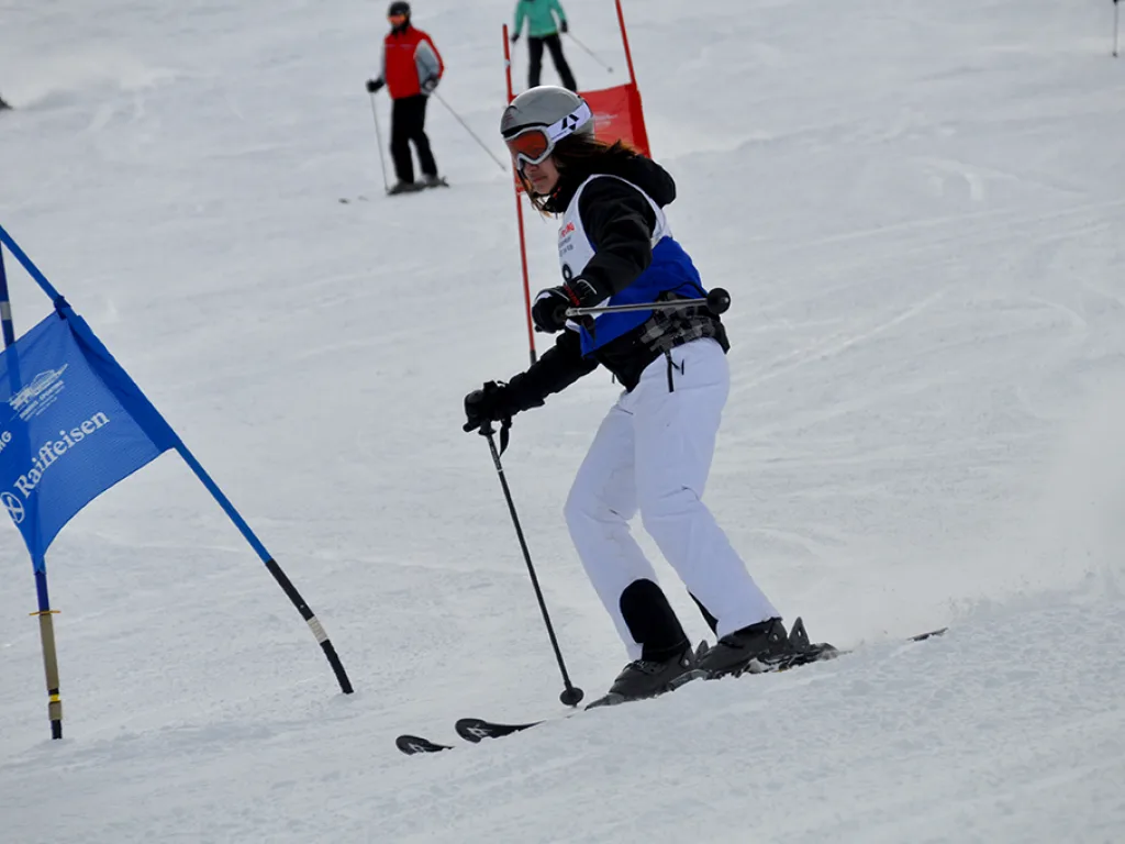 Snowboarderin in weißer Hose fährt neben einem blauen Tor.